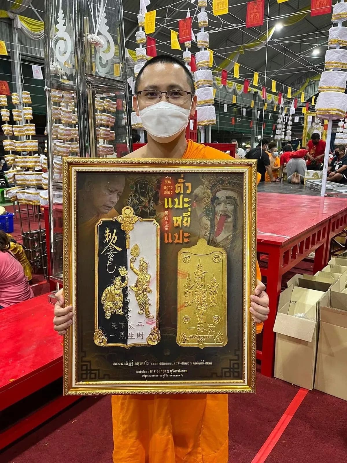 พระสงฆ์ถือกรอบรูปเหรียญตั่วแปะยี่แปะเนื้อทองในมณฑลพิธี